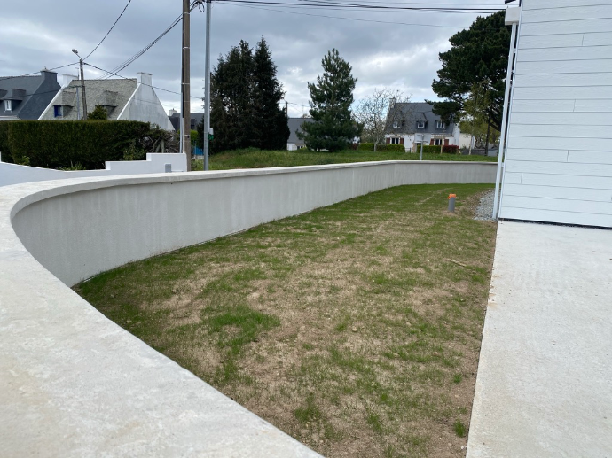Mur courbé avec enduit ciment pour aménagement extérieur par Quéré Paysages à Concarneau